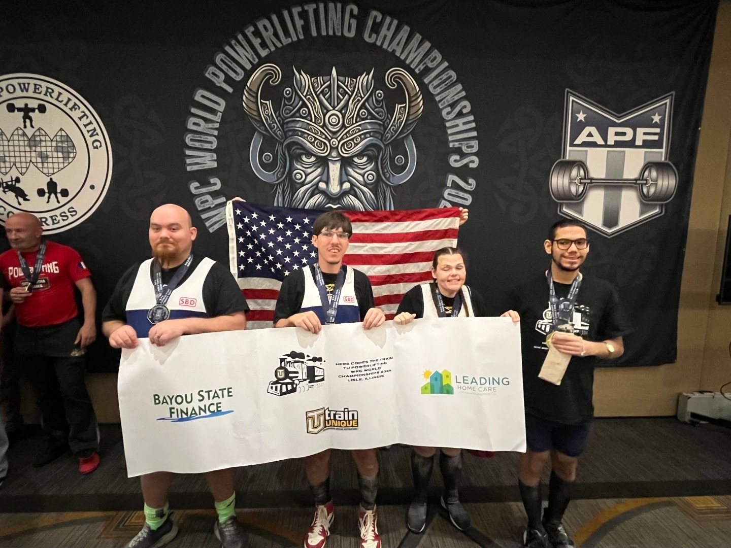 Train Unique athletes and coaches with an American flag and team banner at the WPC World Powerlifting Championships